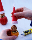 Walnut Father Christmas (5/6). Glue red cap on Juglans (walnut), citrus (lime slice) as nose, toothpick as beard