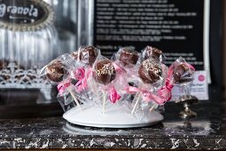 Vegan cake pops gift-wrapped in transparent cellophane and displayed on a stand