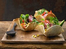 A mexican salad with spicy beef in a tortilla basket