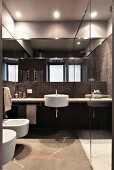 Designer bathroom with dark tiles and round white sink