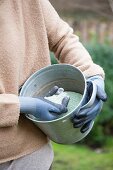 Woman holding zinc bucket of granules