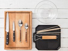 Kitchen utensils for making tamarind chicken skewers with a salad