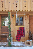 Re blanket and cushion on hanging chair on veranda of cabin