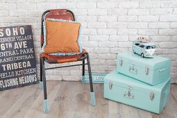 Mintfarbene Koffer, Lederstuhl mit gestrickten Stulpen und Retro-Schilder