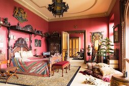 Ornate carved bed in red bedroom with tiger-skin rug