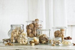 Various types of nut in glass jars on a rustic kitchen table