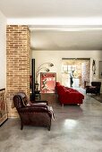 Leather armchair and red couch in living area with view into open-plan kitchen