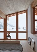 Schlafzimmer im modernen Holzhaus mit Blick auf Winterlandschaft