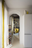 Vertikales Bücherregal vor dem Durchgang ins Wohnzimmer