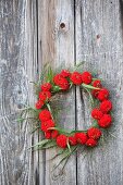 Wreath of red zinnias and switchgrass hung from board wall