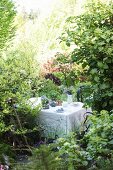 Painted tablecloth and jug vase on table on garden terrace