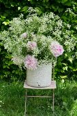 Enamel bucket of chervil and peonies on garden chair