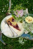 Gartenpicknick auf einem Stuhl mit Kuchen, Pudding und Blumen