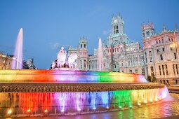 The Palacio de Cibeles with the colourfully illuminated Fuente de Cibeles fountain in Madrid, Spain