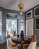 Designer chairs around antique pedestal table in connecting room