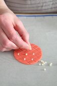 Sugar pearls being applied to a quilted pattern cake decoration
