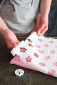 A sheet of fondant icing with cut-out flowers for a cake board