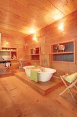 White, free-standing bathtub in wood-panelled bathroom