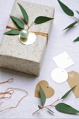 Geschenk mit Weihnachtskugel und Blätterzweig dekoriert