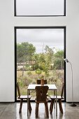 Solid wooden chair in minimalist dining area in front of large window