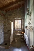 Sloping, wood-beamed ceiling and stone walls in bathroom
