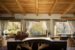 Country-house-style attic bedroom with glass wall and view of woodland