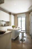 Island counter and bar stools in white, contemporary fitted kitchen