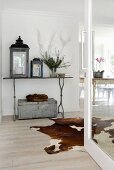 Lanterns on metal table and cow-hide rug in foyer