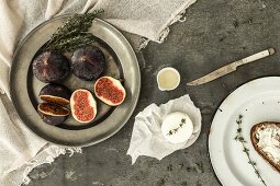 A still life with figs, goat's cheese, thyme, honey and Bauernbrot (German farmhouse bread)
