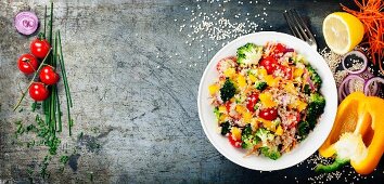 Quinoasalat mit Brokkoli, Paprika, Karotten, Zwiebeln und Tomaten auf einem rustikalem Metalluntergrund