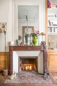 Lit candles in fireplace with large mirror above old mantelpiece