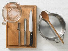 Kitchen utensils: measuring cups, vegetable peeler, knives, pot, wooden spoon