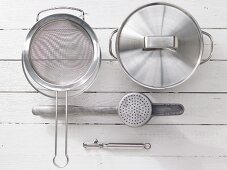 Various kitchen utensils: sieve, cooking pot, potato press, vegetable peeler