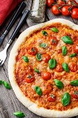 Pizza Margherita mit Tomaten und Basilikum auf Holztisch (Italien)