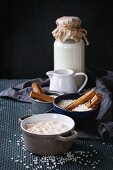 Ingredients for making rice pudding: white uncooked rice, sugar, cinnamon sticks, milk, cream and pot of cooking pudding