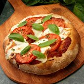 Ganze Vollkorn Pizza mit Tomate, Mozzarella und Basilikum auf Pizzaschieber