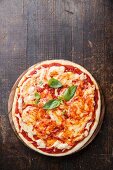 Pizza Margheritaa mit Basilikum auf Holztisch