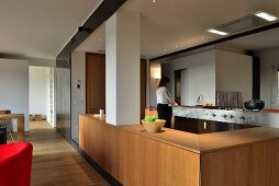 Open-plan fitted kitchen with woman in background