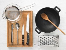 Various kitchen utensils: wok, grater, strainer, vegetable peeler, knives