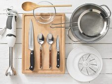 Various kitchen utensils: blender, cutlery, pot, strainer, measuring cup