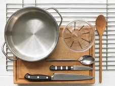 Various kitchen utensils: pot, measuring cup, knives, spoon