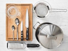 Various kitchen utensils: pot, strainer, grater, citrus press, knives, spoons
