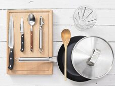 Various kitchen utensils: pan, measuring cup, knives, peeler