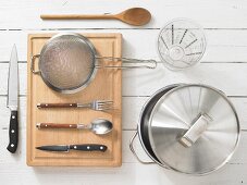 Various kitchen utensils: pot, measuring cup, sieve, knives, spoon