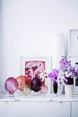 Bunte Glasdekoration und Orchideen auf Lowboard