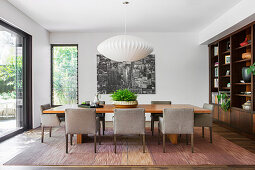 Gray upholstered chairs around large dining table on mottled carpet