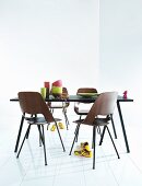 Black dining table, wooden shell chairs and colourful crockery