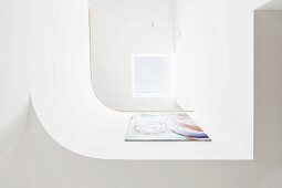 Blick auf gerundete, weiße Brüstung mit Gemälde und hellem Oberlichtfenster