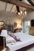 Bed with purple frame below exposed roof beams in bedroom