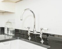 A mixer tap on a glossy black granite kitchen worktop